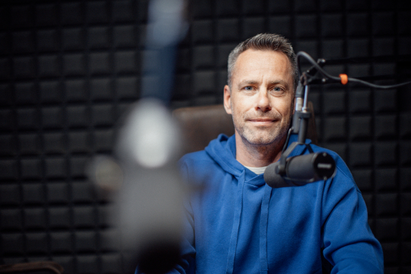 A portrait of mature radio host speaking in microphone while moderating a live show