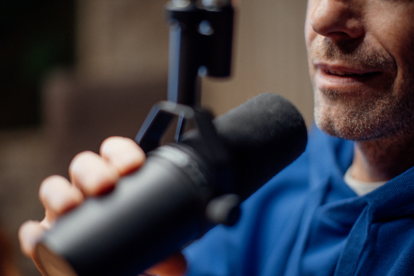 Close-up of a man speaking in microphone during moderating podcast.