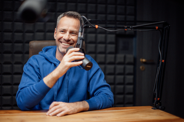 A portrait of mature radio host speaking in microphone while moderating a live show