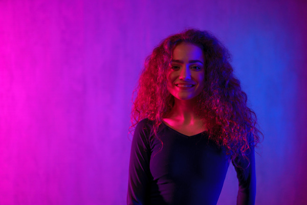 Portrait of a happy woman dancer at disco party with neon background.