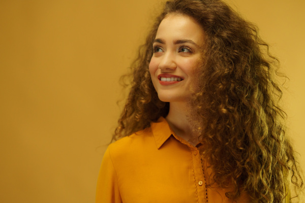 Studio portrait of a happy young woman on yellow background, copy space.