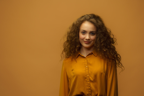 Studio portrait of a happy young woman on yellow background, copy space.