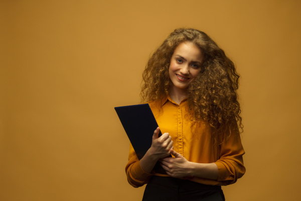 A studio portrait of happy businesswoman holding folder and papers, on yellow background, Business concept. Accountant, copy space.