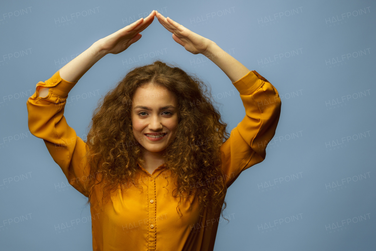 A photo portrait of woman making roof over head with hands isolated on grey background. Life insurance concept.