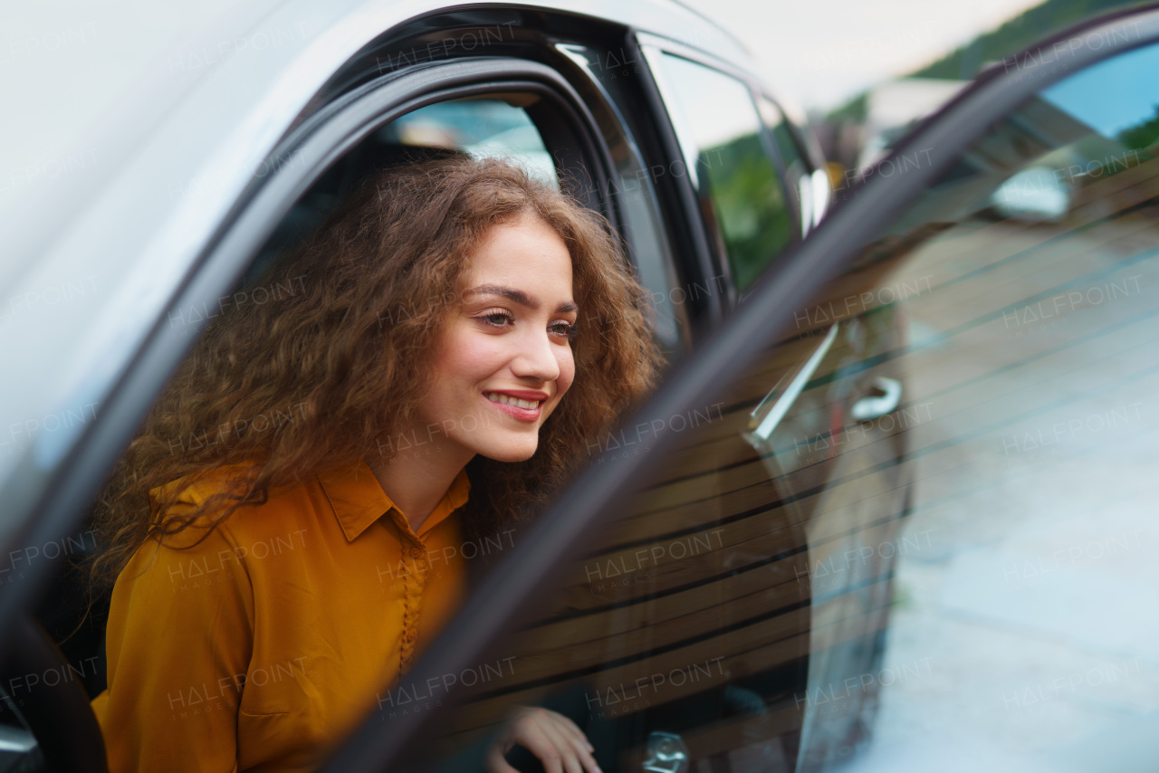 Young woman driver coming out of the car in the city street. Concept of independent and modern woman.