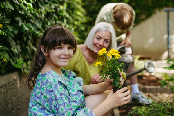 Portrait of cute schoolgirl taking care of plants in school garden during at outdoor sustainable education class.Concept of experiential learning, ecoliteracy.