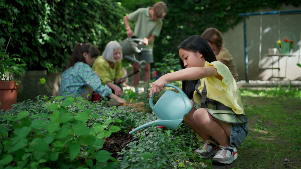 Students and female teacher at outdoor sustainable education class. Kids taking care of plants in school garden. Concept of experiential learning, ecoliteracy.