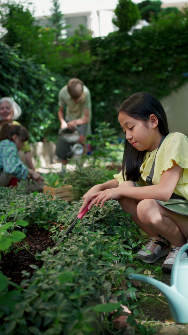 Students and female teacher at outdoor sustainable education class. Kids taking care of plants in school garden. Concept of experiential learning, ecoliteracy.