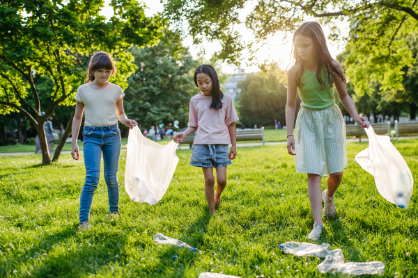 Students on nature walk picking plastic litter, environmental cleanup during outdoor sustainable education class. Concept of experiential learning, ecoliteracy.