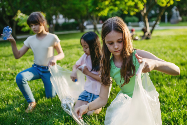 Students on nature walk picking plastic litter, environmental cleanup during outdoor sustainable education class. Concept of experiential learning, ecoliteracy.