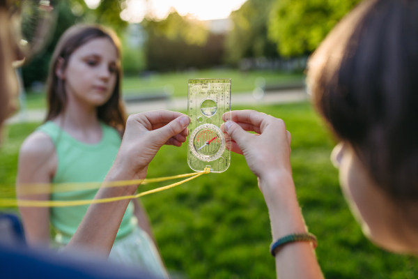 Group of children in outdoor sustainable educational class using compass learning orienteering in public park.