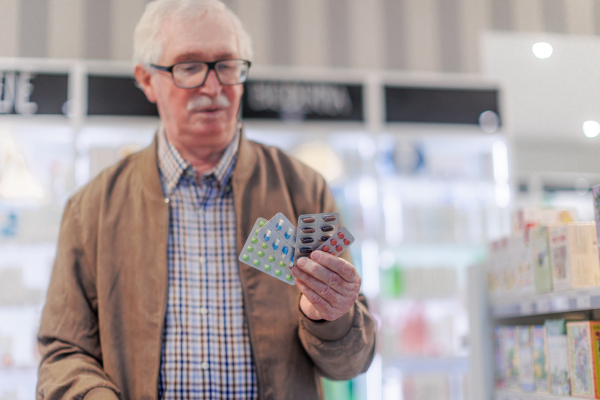 Close up of senior holding pills in a pharmacy store.