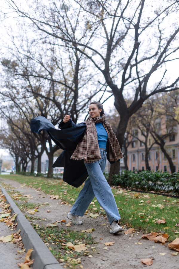 Young woman walking outdoor, in an autumn city.