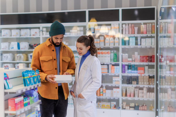 Young pharmacist helping customer to choos a medication.