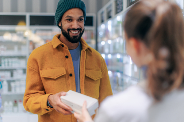 Young pharmacist helping customer to choos a medication.