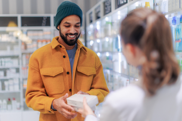 Young pharmacist helping customer to choos a medication.