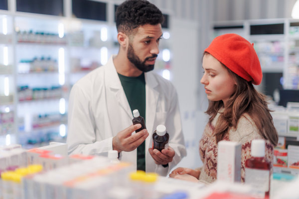 Young pharmacist helping customer to choos a medication.