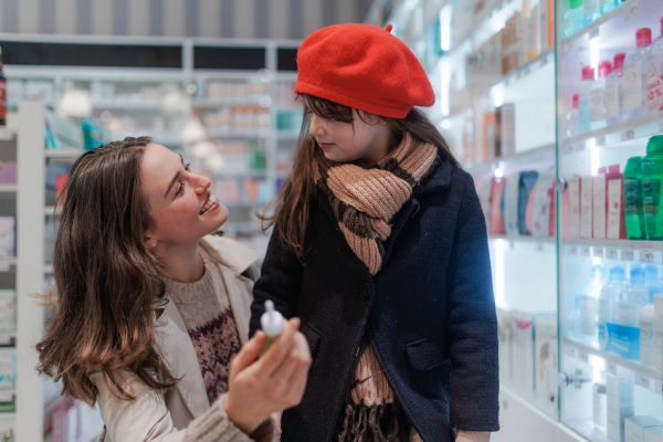 Young woman with her daughter choosing a medication in a pharmacy store.