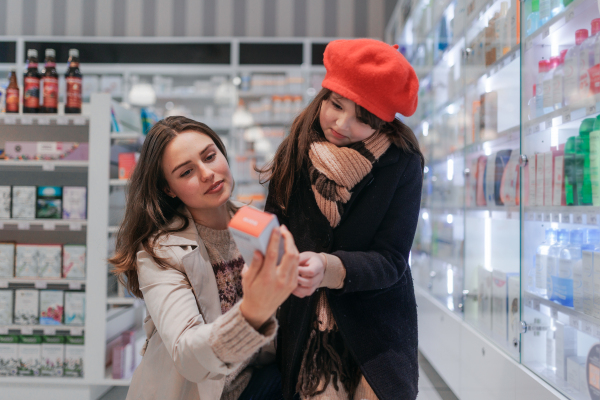 Young woman with her daughter choosing a medication in a pharmacy store.