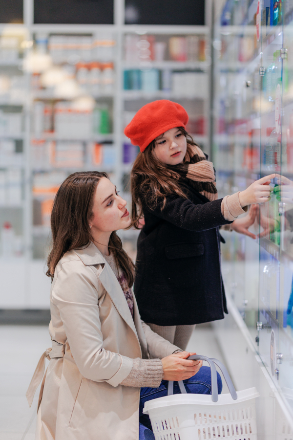 Young woman with her daughter choosing a medication in a pharmacy store.