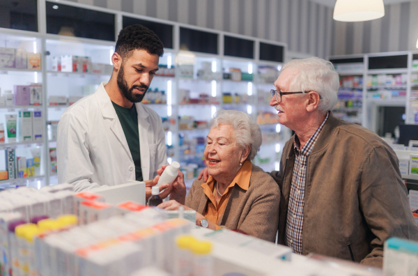 Young pharmacist helping senior couple to choos a medication.