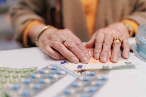 Close-up of senior woman paying for pills in pharmacy.