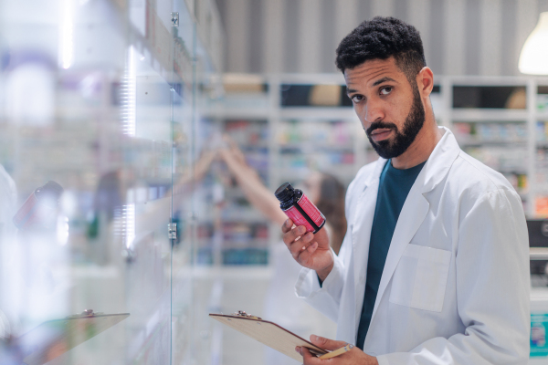 Young pharmacist checking medicine stock in a pharmacy.