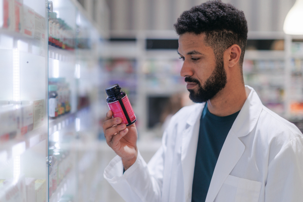 Young pharmacist checking medicine stock in a pharmacy.