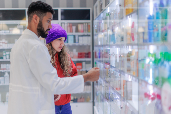 Young pharmacist helping customer to choos a medication.