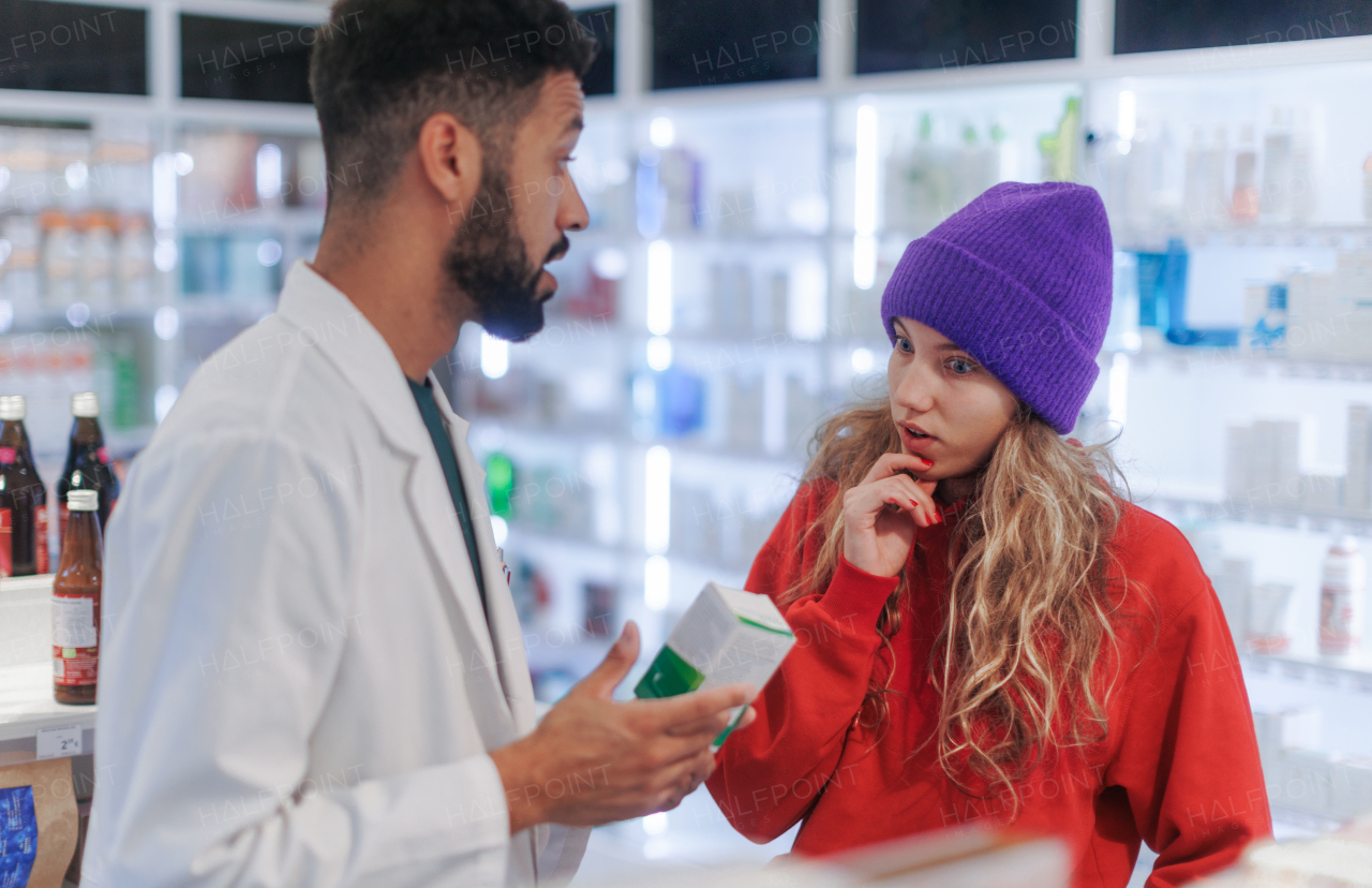 Young pharmacist helping customer to choos a medication.