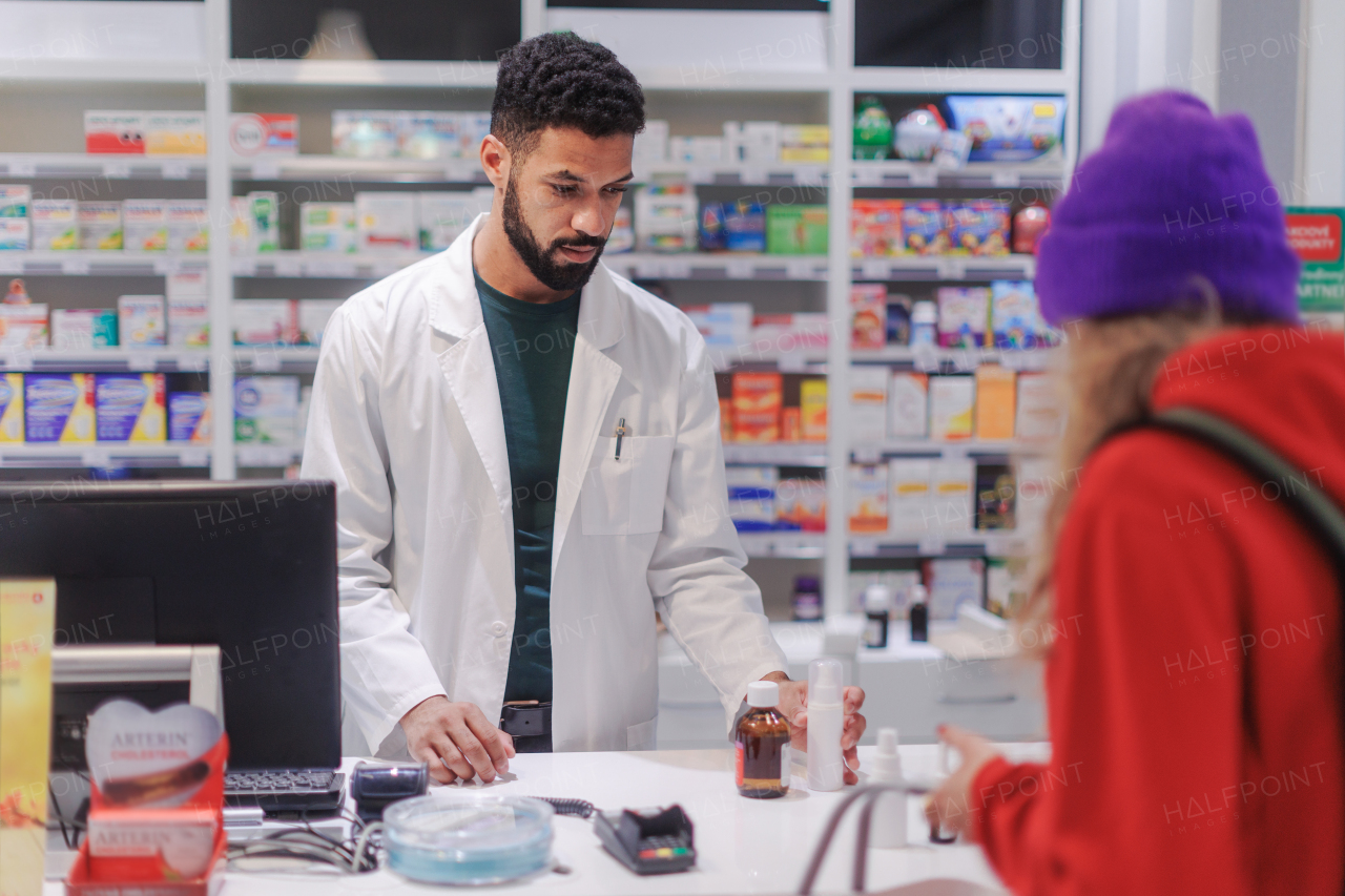 Multiracial pharmacist selling medications to young girl.