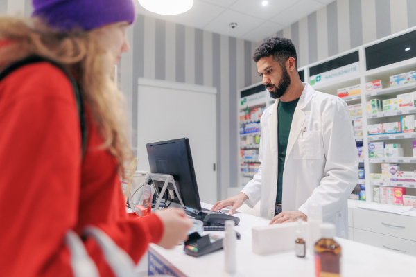 Multiracial pharmacist selling medications to young girl.