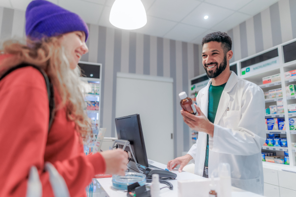 Multiracial pharmacist selling medications to young girl.