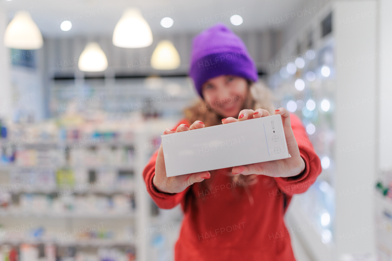 Portrait of a young girl holding box with pills in a pharmacy store.