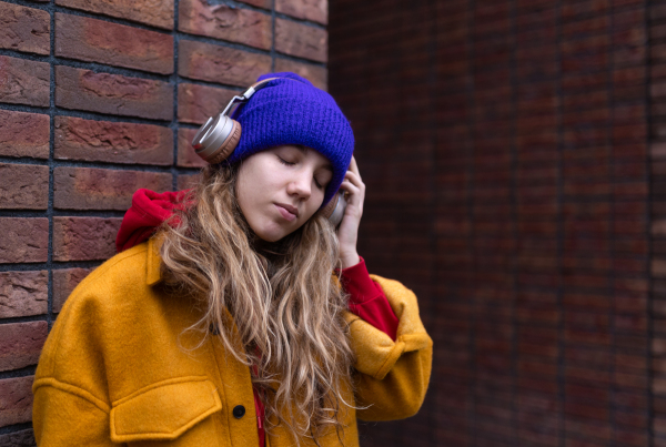 Young woman listening music outdoor, in city.