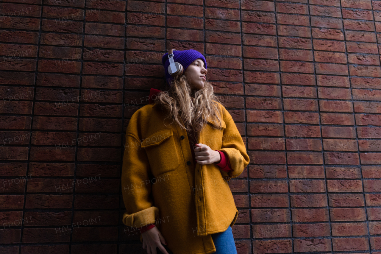 Young woman listening music outdoor, in city.