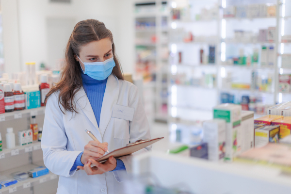 Young pharmacist checking medicine stock in a pharmacy.