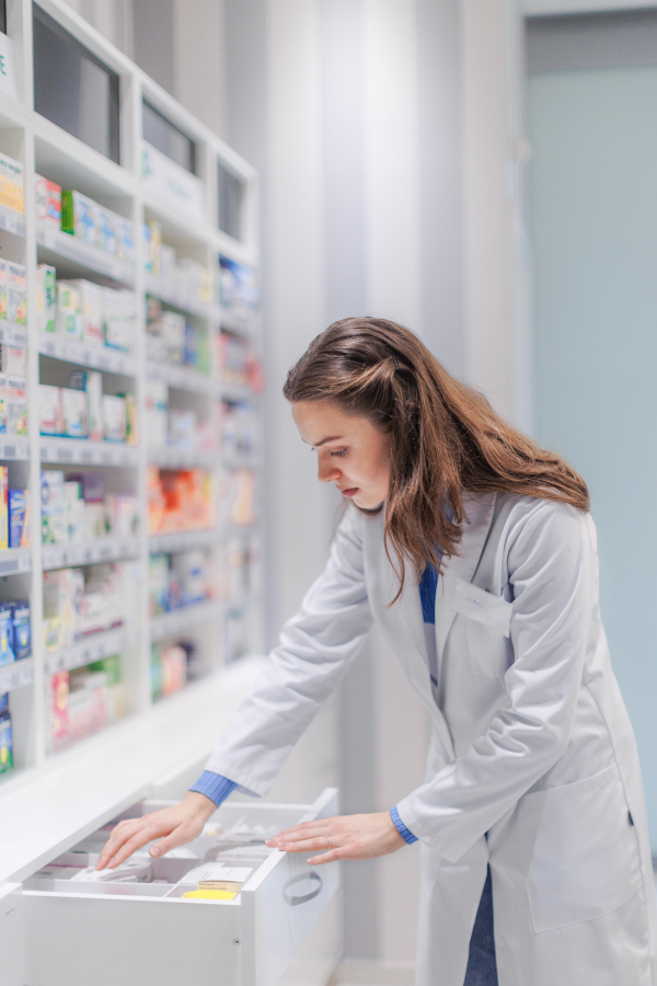 Young pharmacist checking medicine stock in a pharmacy.