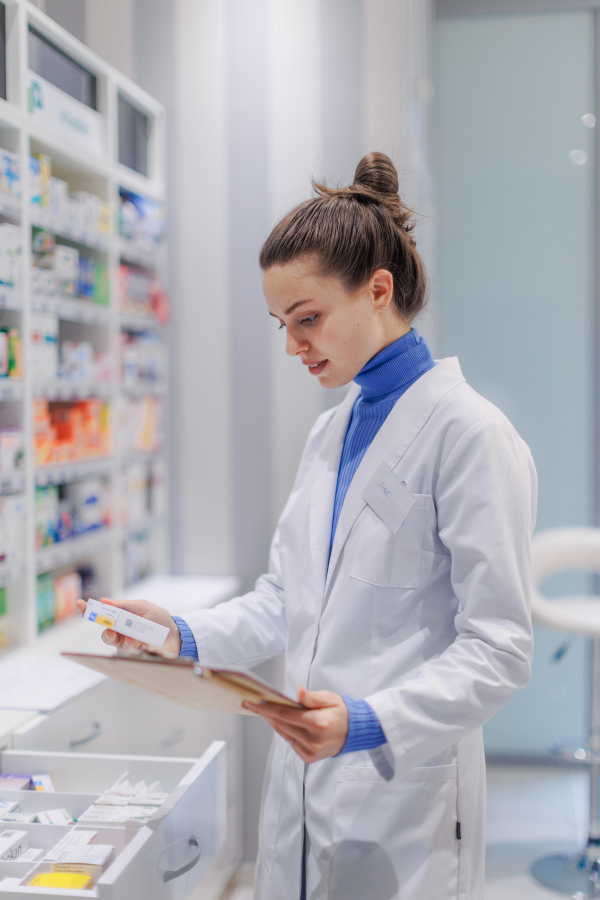 Young pharmacist checking medicine stock in a pharmacy.