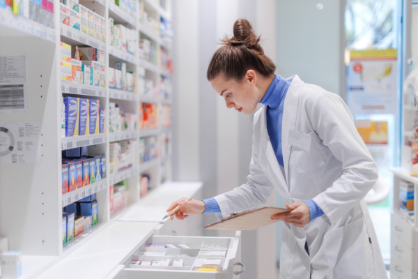 Young pharmacist checking medicine stock in a pharmacy.