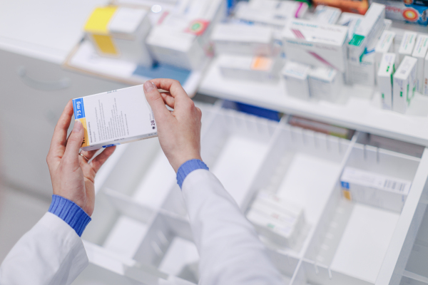 Close-up of pharmacist holding medicines in pharmacy.