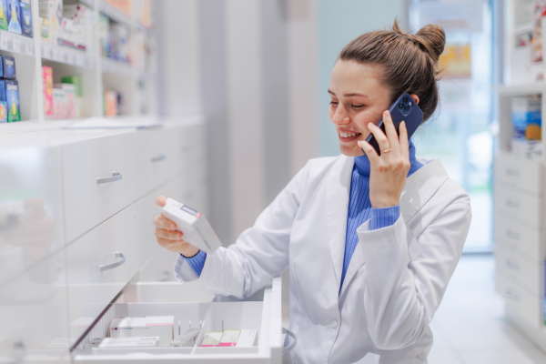 Young pharmacist checking medicine stock in a pharmacy.