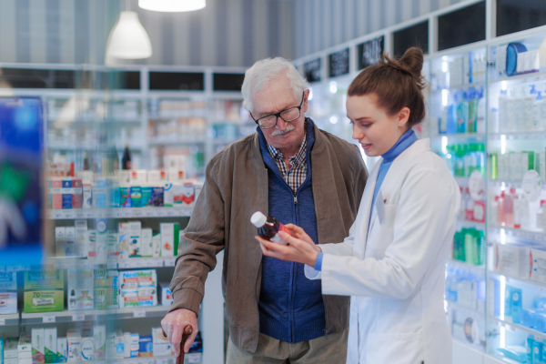 Young pharmacist helping senior man to choos a medication.