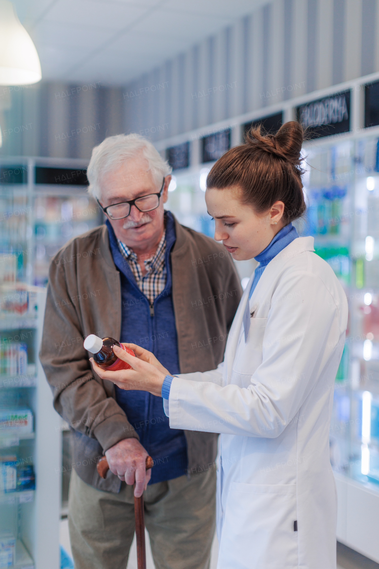 Young pharmacist helping senior man to choos a medication.