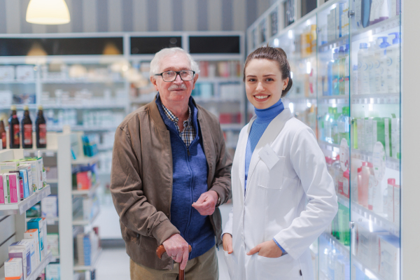 Portrait of young pharmacist and senior man in a pharmacy store.