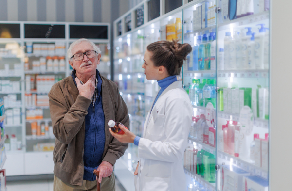 Young pharmacist helping senior man to choos a medication.