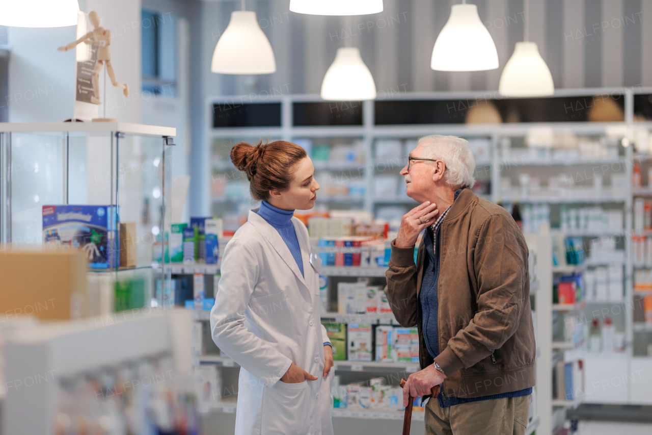 Young pharmacist helping senior man to choos a medication.