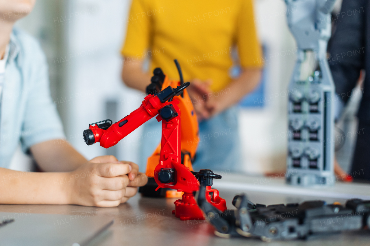 Close up on children looking at small robot, learning robotics in elementary school. Young students building robot in after school robotics club.