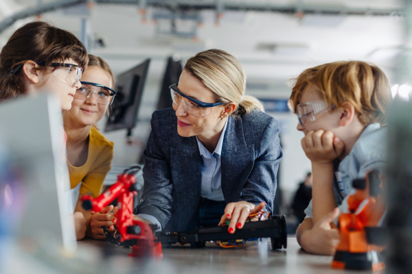 Children learning robotics in Elementary school. Young students building robot in after school robotics club. Field trip to real robotics laboratory.