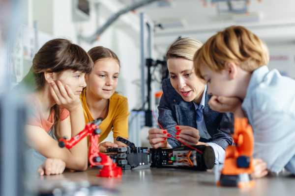 Children learning robotics in Elementary school. Young students building robot in after school robotics club. Field trip to real robotics laboratory.